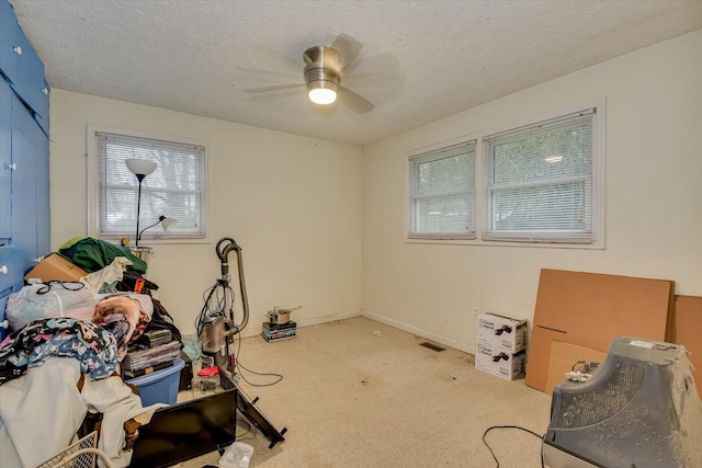 exercise room with ceiling fan, light colored carpet, and a textured ceiling