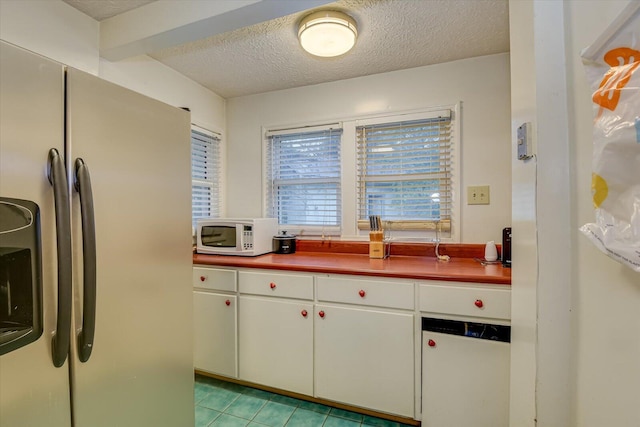 kitchen with stainless steel fridge, a textured ceiling, and white cabinets