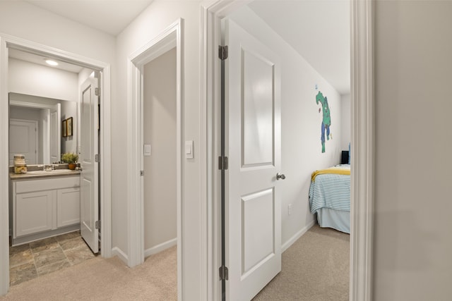 hallway featuring light colored carpet and sink