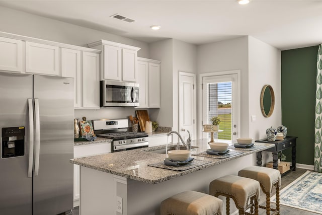 kitchen with light stone countertops, white cabinets, dark hardwood / wood-style flooring, stainless steel appliances, and sink