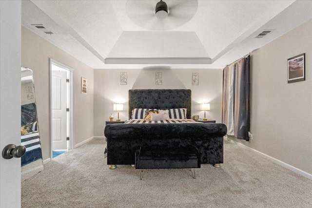 carpeted bedroom with a tray ceiling and ceiling fan