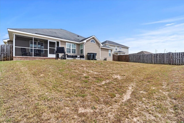 back of house featuring a lawn and a sunroom