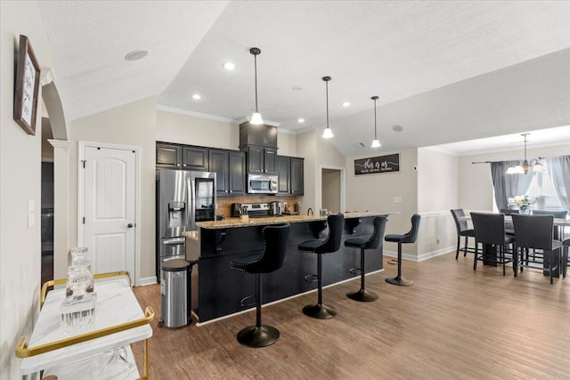 kitchen with a kitchen breakfast bar, lofted ceiling, decorative light fixtures, and appliances with stainless steel finishes