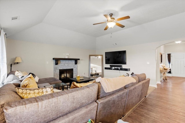 living room featuring a stone fireplace, ceiling fan, light hardwood / wood-style flooring, and lofted ceiling