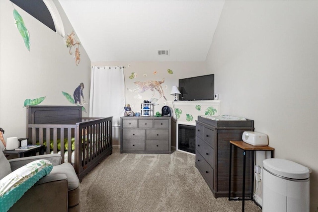 carpeted bedroom with a crib and vaulted ceiling