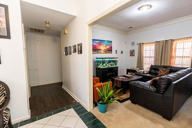 living room with a textured ceiling, tile patterned flooring, visible vents, and crown molding