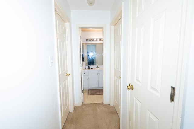 hall featuring a sink and light colored carpet