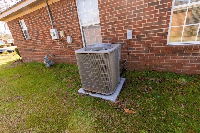 exterior details with electric meter, central AC unit, gas meter, and brick siding