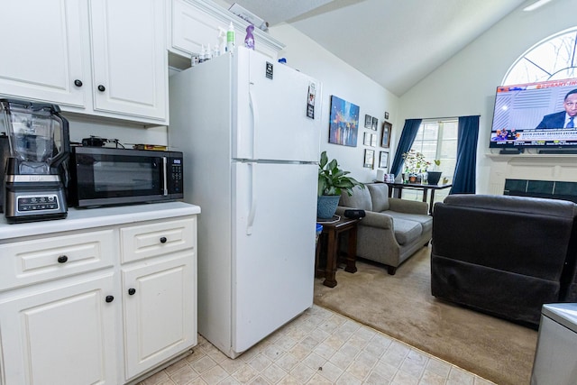 kitchen with light countertops, freestanding refrigerator, open floor plan, white cabinets, and black microwave