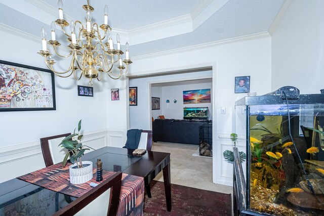 dining area with a decorative wall, a wainscoted wall, a notable chandelier, ornamental molding, and a raised ceiling