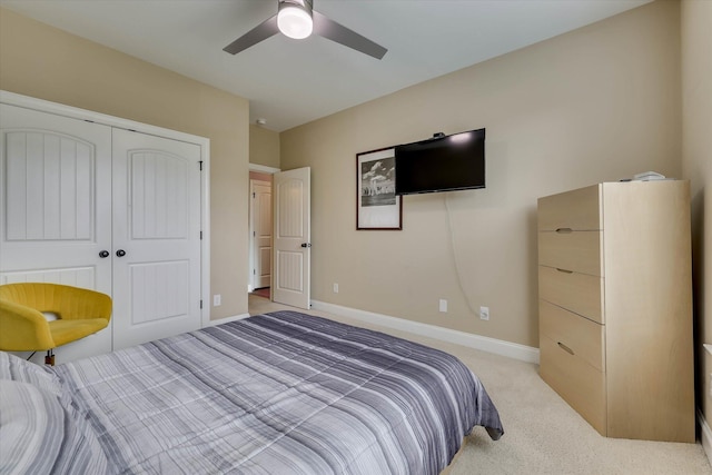bedroom with a closet, ceiling fan, light colored carpet, and baseboards