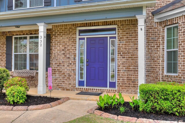 entrance to property featuring covered porch and brick siding
