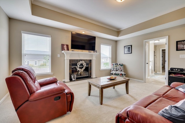 living area featuring ornamental molding, light carpet, a high end fireplace, baseboards, and a raised ceiling