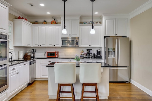 kitchen with white cabinets, stainless steel appliances, dark countertops, and a sink