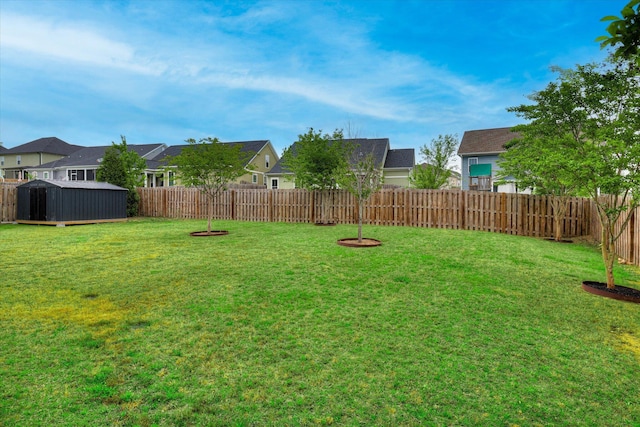 view of yard with an outdoor structure, a storage shed, a residential view, and a fenced backyard