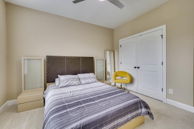 bedroom with a closet, ceiling fan, light carpet, and baseboards