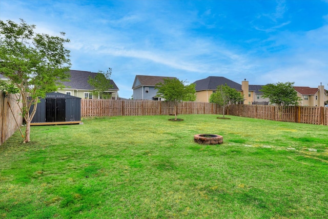 view of yard featuring a storage shed, an outdoor fire pit, and a fenced backyard