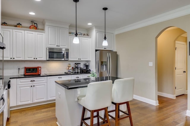 kitchen featuring arched walkways, white cabinets, appliances with stainless steel finishes, and light wood-type flooring