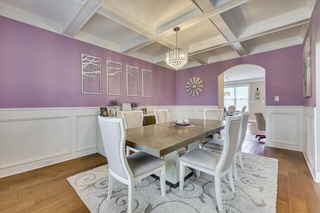 dining area featuring coffered ceiling, beamed ceiling, and arched walkways