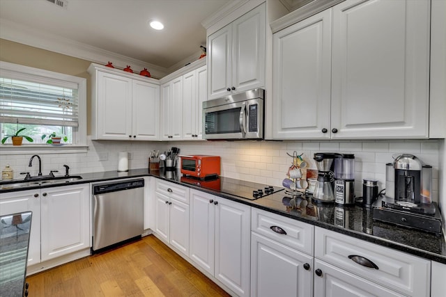 kitchen featuring a sink, light wood-type flooring, crown molding, white cabinetry, and appliances with stainless steel finishes
