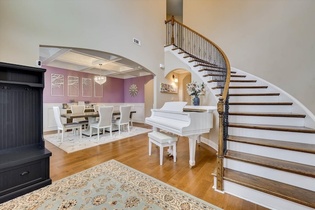 interior space with stairway, coffered ceiling, visible vents, arched walkways, and wood finished floors