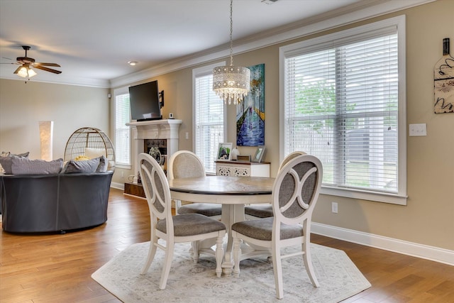 dining room with a fireplace, ceiling fan with notable chandelier, ornamental molding, and a healthy amount of sunlight