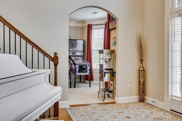 entryway with ornamental molding, arched walkways, visible vents, and a healthy amount of sunlight