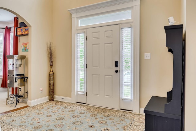 foyer entrance featuring baseboards and arched walkways
