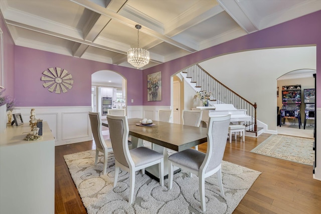 dining space with an inviting chandelier, stairway, beam ceiling, coffered ceiling, and arched walkways