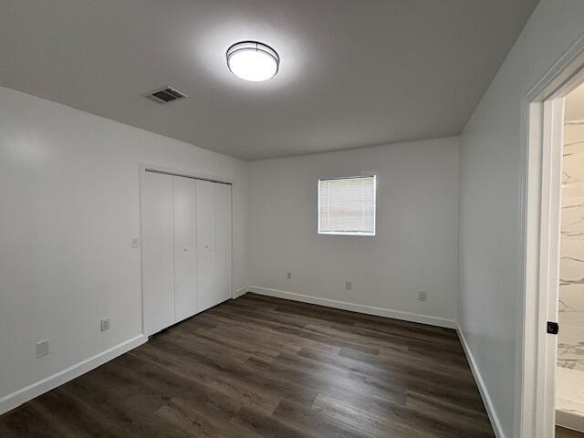 641 Ellington Ave, Thomson, GA 30824 - unfurnished bedroom featuring baseboards, dark wood-type flooring, ensuite bathroom, and a closet