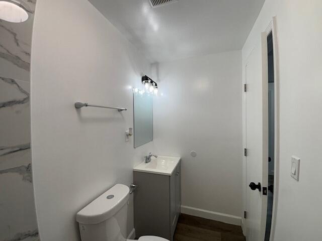 641 Ellington Ave, Thomson, GA 30824 - bathroom featuring vanity, toilet, baseboards, and wood finished floors