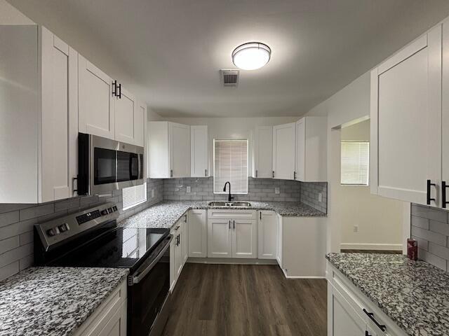 641 Ellington Ave, Thomson, GA 30824 - kitchen with appliances with stainless steel finishes, a sink, dark wood-style floors, light stone countertops, and tasteful backsplash