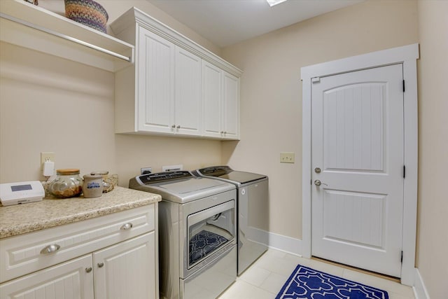 laundry area with cabinets, washer and clothes dryer, and light tile patterned flooring