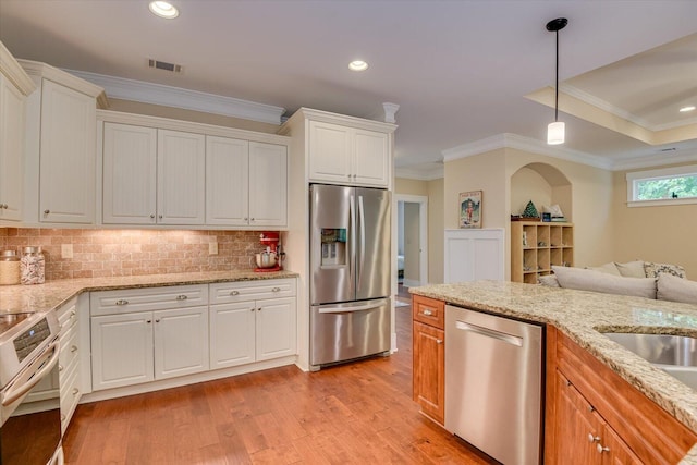 kitchen featuring tasteful backsplash, light stone counters, decorative light fixtures, white cabinets, and appliances with stainless steel finishes