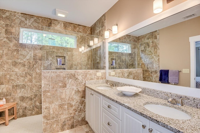 bathroom featuring tiled shower, tile walls, and vanity