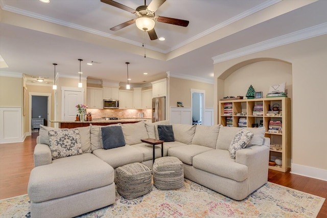 living room with ceiling fan, wood-type flooring, and crown molding