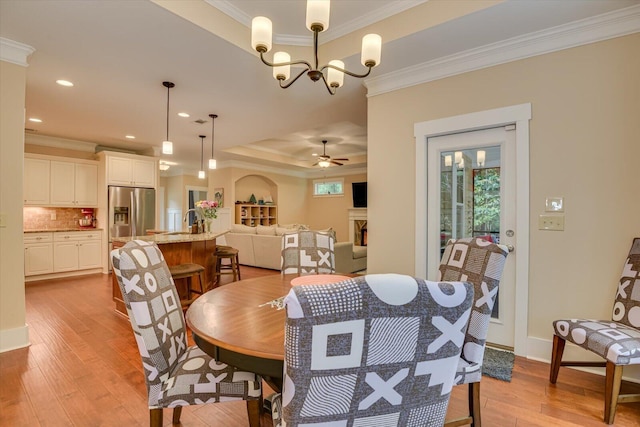 dining space featuring ceiling fan with notable chandelier, light hardwood / wood-style floors, and crown molding