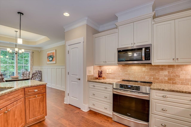 kitchen featuring white cabinets, light stone counters, appliances with stainless steel finishes, and an inviting chandelier