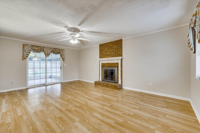 unfurnished living room featuring a textured ceiling, ornamental molding, ceiling fan, a fireplace, and light hardwood / wood-style floors