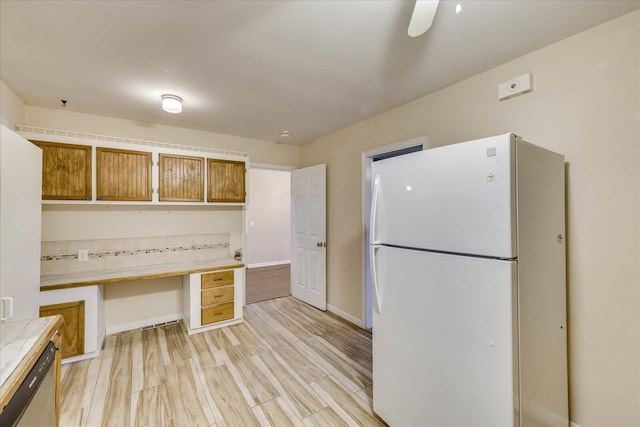 kitchen featuring built in desk, dishwasher, white fridge, ceiling fan, and light wood-type flooring