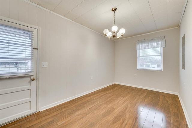 unfurnished room with hardwood / wood-style floors, crown molding, a notable chandelier, and electric panel