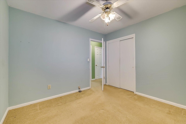 unfurnished bedroom featuring ceiling fan, light colored carpet, and a closet