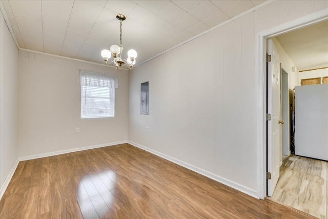 unfurnished room with wood-type flooring, ornamental molding, and a notable chandelier