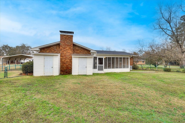 rear view of house with a yard, a sunroom, and a carport