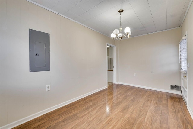 unfurnished room with a notable chandelier, ornamental molding, hardwood / wood-style floors, and electric panel