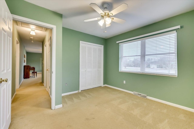 unfurnished bedroom with light colored carpet, a closet, and ceiling fan