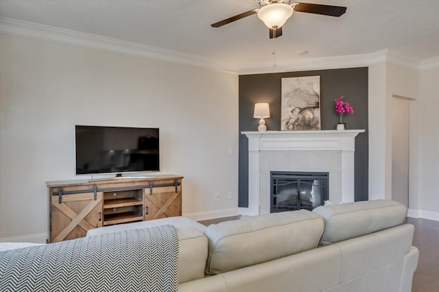 living room with a tile fireplace, ornamental molding, and ceiling fan