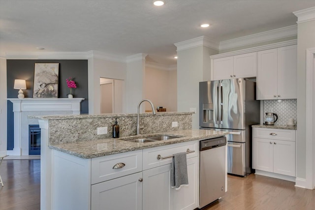 kitchen with sink, light wood-type flooring, stainless steel appliances, a kitchen island with sink, and white cabinets