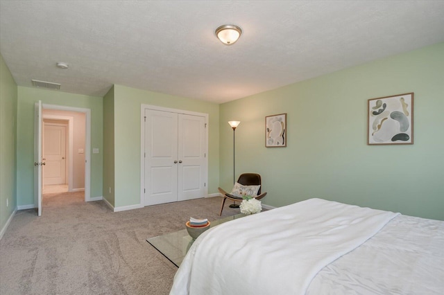 bedroom with a closet, light carpet, and a textured ceiling