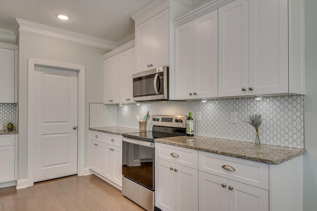 kitchen featuring appliances with stainless steel finishes, backsplash, white cabinets, ornamental molding, and light stone counters